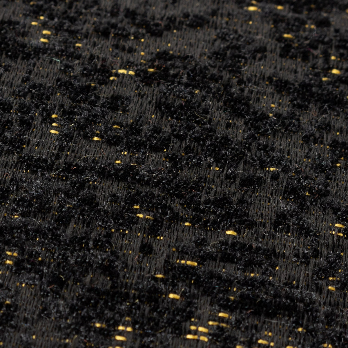 Close-up of the Galaxy Eyelet Chenille Cushion in black, showing textured chenille pile with fine gold flecks woven through the tufting.