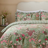 Gardenia Reversible Botanical Duvet Cover Set in Pink Forest, shown on a bed with pink and cream floral print on sage green, ruffled pillow shams, and green wavy-striped reverse.