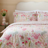 Gardenia Reversible Botanical Duvet Cover Set in Pink Pebble, styled on a bed with frilled-edge pillowcases in a pink and green floral print, shown in a bedroom setting.