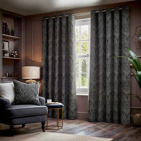 Gatsby Jacquard Lined Eyelet Curtains in black with champagne feathered arc pattern, hung by a window in a living room with matching cushion and armchair.