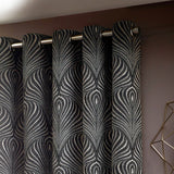 Gatsby Jacquard Lined Eyelet Curtains in black, showing feathered Art Deco-style pattern in champagne and gold tones, hung on a metal pole with eyelet fittings.