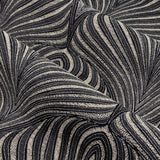 Close-up of Gatsby Jacquard Lined Eyelet Curtains in black, showing a woven feathered arc pattern in champagne and gold tones with a subtle metallic sheen.