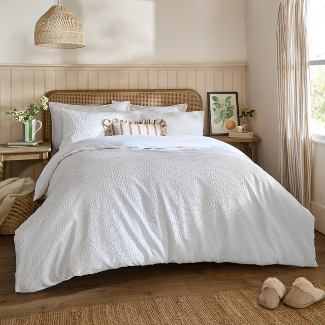 Georgia Woven Polycotton Duvet Cover Set in white with textured pattern, styled on a bed with matching pillowcases and a striped accent cushion in a bedroom setting.