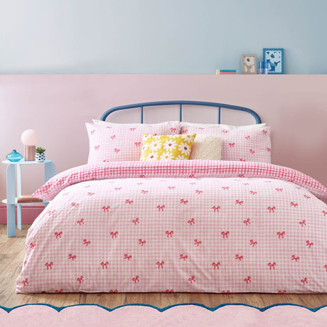 Gingham Bows Reversible Check Duvet Cover Set in pink, dressed on a bedroom bed with matching pillowcases, pink bow-print gingham front and bold check reverse.