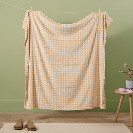 Gingham Check Polyester Throw in Yellow, a plush fleece throw with a pale yellow and white check pattern, pegged on a washing line against a green wall.
