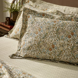 Golden Lily cotton damask duvet cover set on a bed, showing pillow shams with a natural and gold floral lily and tulip pattern, styled in a bedroom setting.
