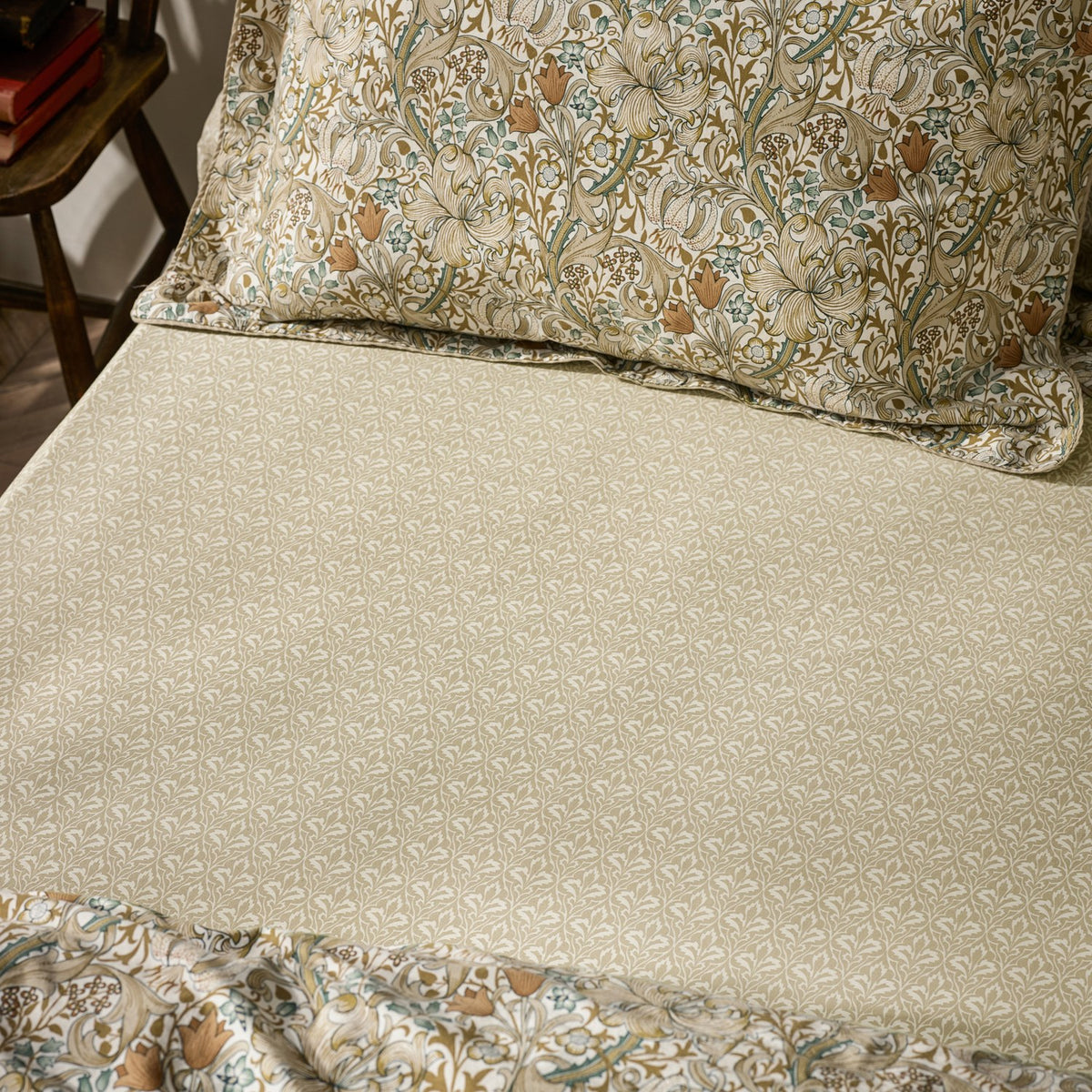 Golden Lily Percale Cotton Fitted Sheet in natural and sage green small-scale botanical trellis print, shown on a bed with a coordinating floral pillowcase.