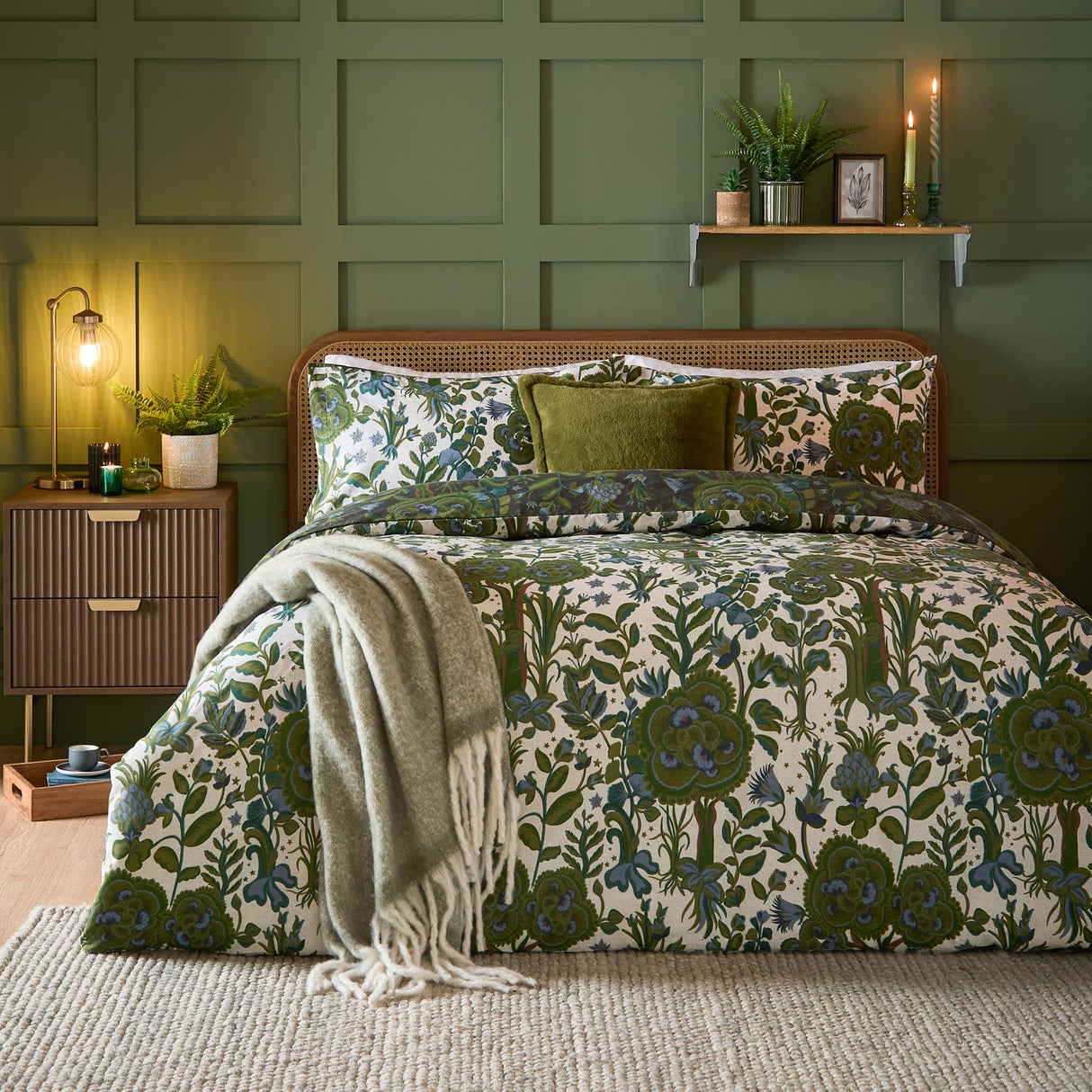 Garden of Wonder Reversible Floral Duvet Cover Set in Evergreen, styled on a bed with matching pillowcases and a green cushion in a green panelled bedroom.