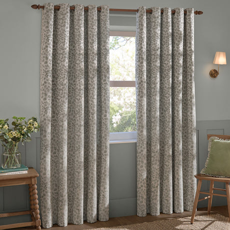 Grace Leaf Jacquard Fully Lined Eyelet Curtains in mist grey, shown as a pair on a wooden pole in a living room, with woven leaf pattern and grommet top.