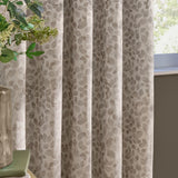Grace Leaf Jacquard eyelet curtains in natural, showing fully lined fabric with a woven trailing leaf pattern hung in soft folds beside a window.