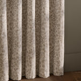 Grace Leaf Jacquard Fully Lined Eyelet Curtains in natural, showing floor-length folds with a woven leaf pattern in muted beige tones against a light wall.