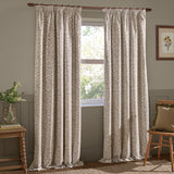 Grace Leaf Jacquard pencil pleat curtains in natural beige with a woven leaf pattern, hung on a wooden pole beside a window in a living room.