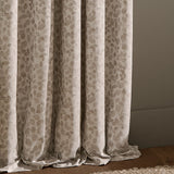 Grace Leaf Jacquard pencil pleat curtains in natural beige polyester, showing draped folds with a woven trailing leaf pattern above a wooden floor.