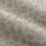 Close-up of Grace Leaf Jacquard pencil pleat curtain fabric in natural beige, showing a woven trailing leaf pattern on a matt satin polyester ground.
