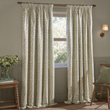 Grace Leaf Jacquard pencil pleat curtains in sage on a wooden pole, showing the leaf pattern woven in green on cream fabric in a living room setting beside a window.