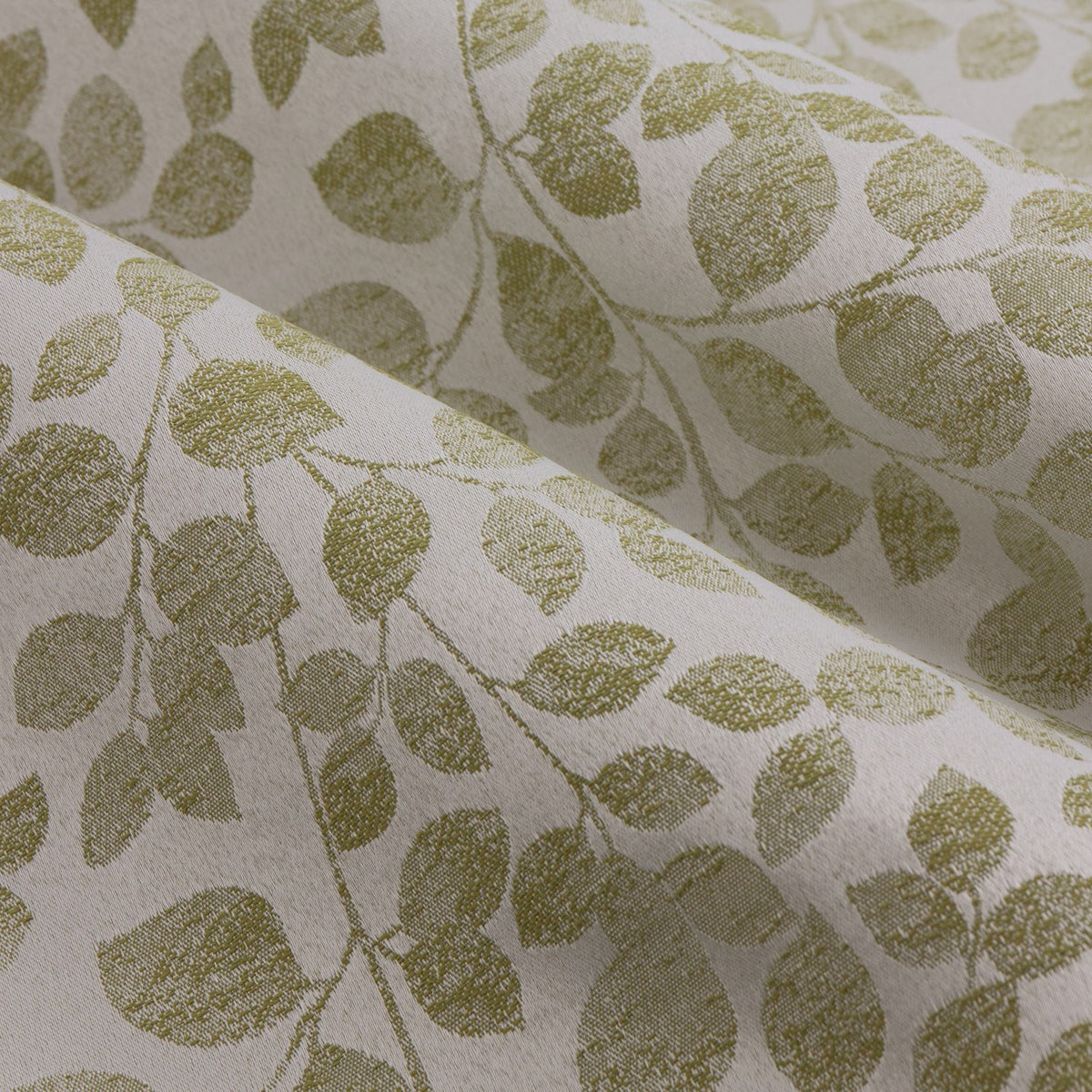 Close-up of Grace Leaf pencil pleat curtains in sage, showing a jacquard-woven trailing leaf pattern in green on a cream polyester ground with a soft fold.