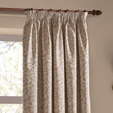 Grace Leaf Jacquard pencil pleat curtains in taupe, shown hanging on a wooden pole with a woven trailing leaf pattern in a living room window setting.