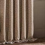 Grace Leaf Jacquard Pencil Pleat Curtains in taupe, pooling in soft folds with a woven leaf pattern, shown against a neutral wall and wood flooring.