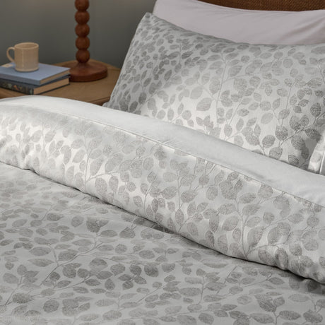 Grace Leaf Jacquard Floral Duvet Cover Set in mist grey, shown on a bed with matching pillowcase, woven leaf pattern in a satin jacquard finish, styled in a bedroom setting.