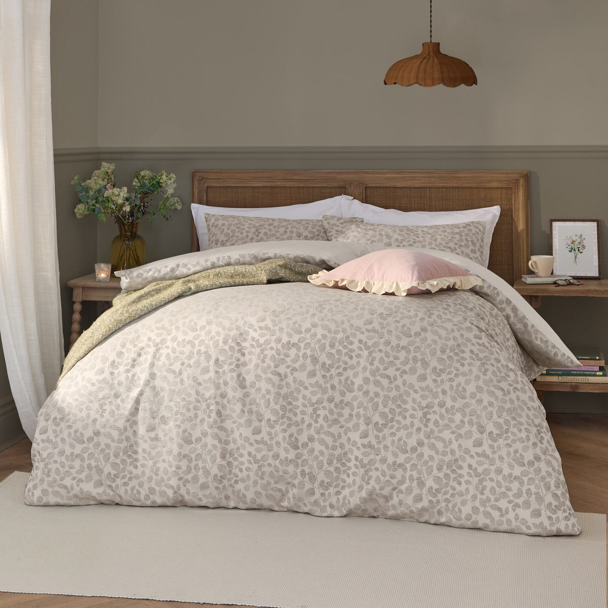 Grace Leaf Jacquard Floral Duvet Cover Set in natural oatmeal on a bed with matching pillowshams, styled with a pink cushion and green throw in a bedroom setting.