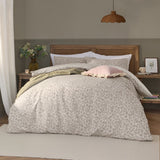 Grace Leaf Jacquard Floral Duvet Cover Set in natural oatmeal on a bed with matching pillowshams, styled with a pink cushion and green throw in a bedroom setting.