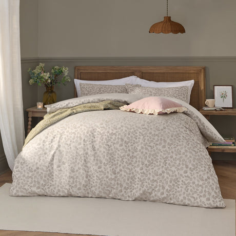 Grace Leaf Jacquard Floral Duvet Cover Set in natural oatmeal on a bed with matching pillowshams, styled with a pink cushion and green throw in a bedroom setting.