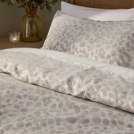 Grace Leaf Jacquard Floral Duvet Cover Set in Natural, showing an oatmeal-toned matt satin jacquard leaf pattern on a duvet and matching pillowcase on a bed.