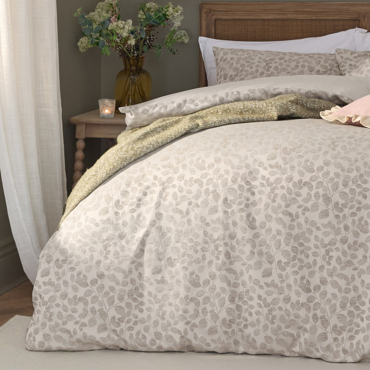 Grace Leaf Jacquard Floral Duvet Cover Set in Natural on a bed with matching pillowcases, oatmeal-toned fabric with a woven leaf pattern, styled in a bedroom with a wooden headboard.