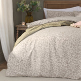 Grace Leaf Jacquard Floral Duvet Cover Set in Natural on a bed with matching pillowcases, oatmeal-toned fabric with a woven leaf pattern, styled in a bedroom with a wooden headboard.