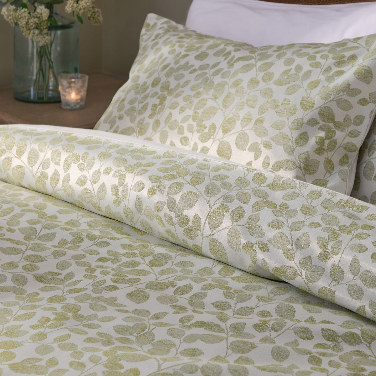 Grace Leaf Jacquard Floral Duvet Cover Set in sage, shown on a bed with matching pillowcase in a woven leaf pattern on a cream ground, styled in a bedroom setting.