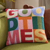 Good Times Tufted Polyester Cushion, a multicoloured 43cm square with "GOOD TIMES" in bold boucle-tufted letters, shown on a green sofa.