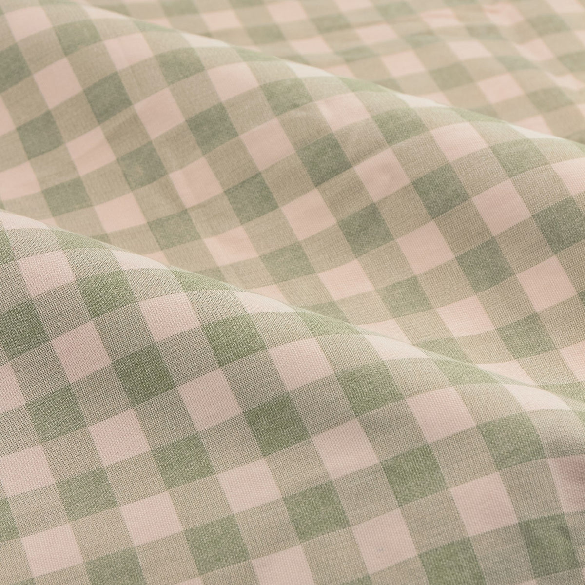 Close-up of Harriet Gingham Check pencil pleat curtain fabric in soft green and pink check on cotton cloth, shown in folded, draped waves.