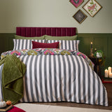 Hallowquin Reversible Striped Duvet Cover Set shown in grey and white on a bed with a Halloween print pillowcase, in front of green wall panelling and a burgundy headboard.