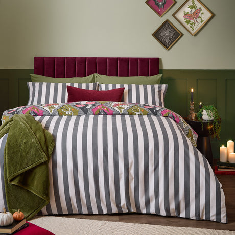 Hallowquin Reversible Striped Duvet Cover Set shown in grey and white on a bed with a Halloween print pillowcase, in front of green wall panelling and a burgundy headboard.
