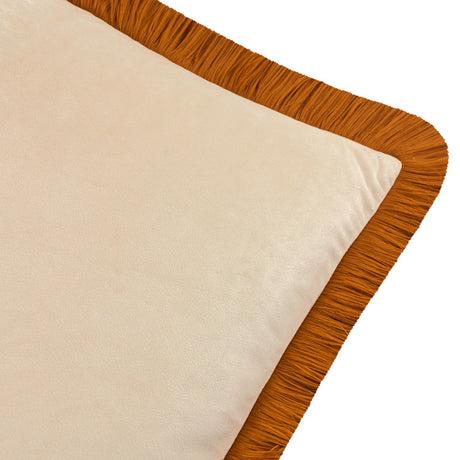Close-up of the Halo Fringed Velvet Cushion showing its plain ecru velvet face bordered by a dense ginger-orange fringed trim, set against a plain white background.
