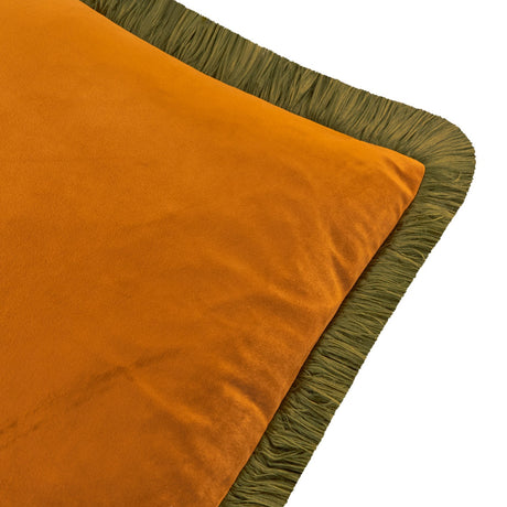 Close-up of the Halo square cushion in ginger orange velvet with a ruched olive-green fringe trim along all edges, shown on a white background.