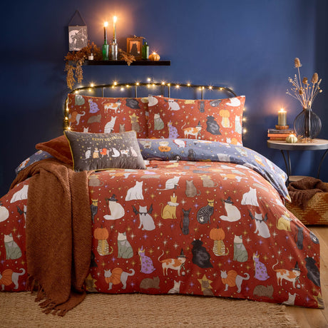 Halloween Pawty Reversible Animal Duvet Cover Set in rust with multicoloured costumed cat print, styled on a bed with matching pillowcases in a dark blue bedroom.