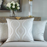 Hamlet Printed Polyester Cushion in Alabaster with a wavy metallic pattern on a cream ground, shown on a sofa alongside textured accent cushions in a living room setting.