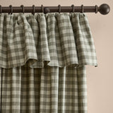 Harriet Gingham cotton pencil pleat curtains in Baygreen/Mist, showing a sage-grey and cream checked pattern with a gathered ruffle flop top, hung from a dark curtain rod.
