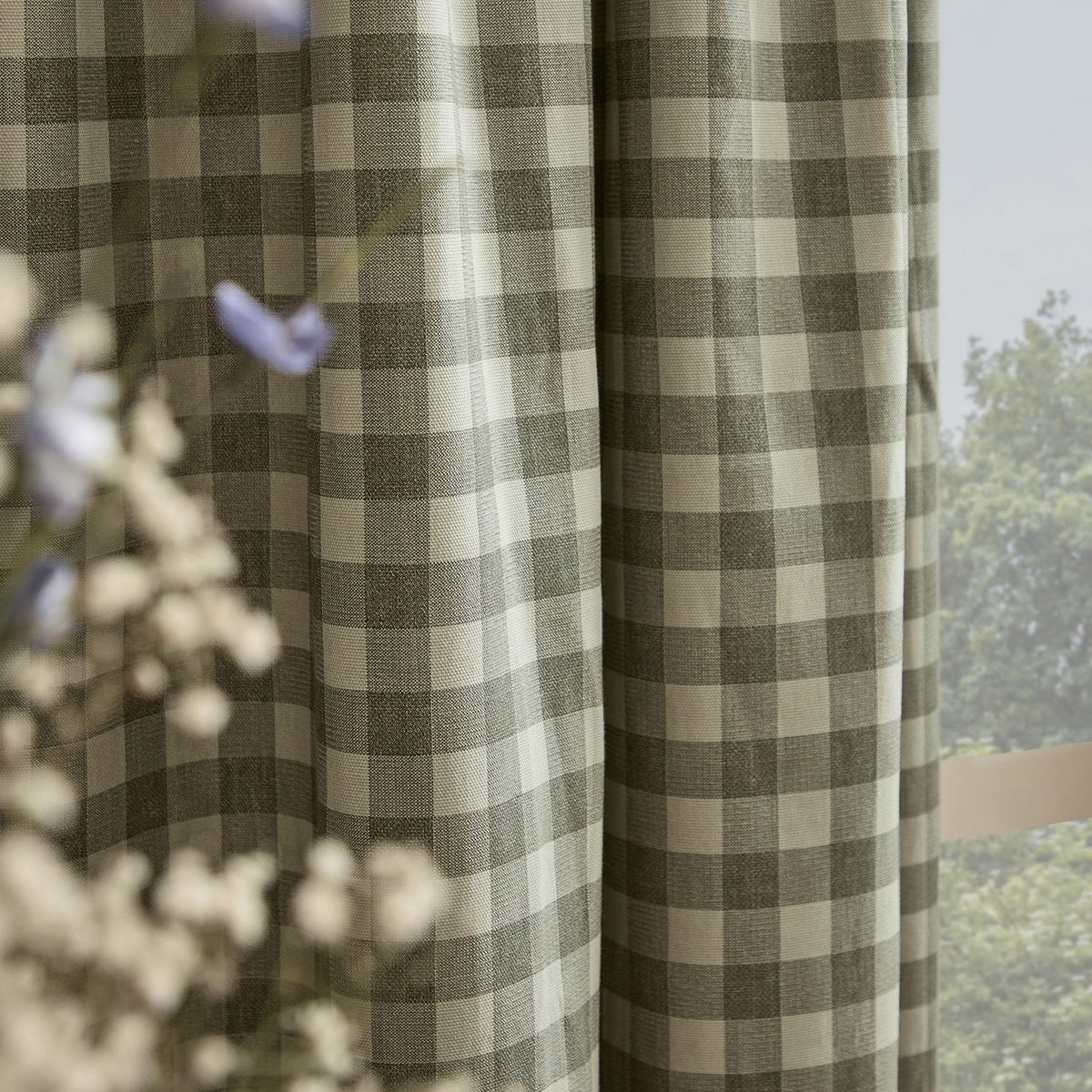 Harriet Gingham cotton pencil pleat curtains in Baygreen/Mist, showing the tonal sage-grey and cream check weave in soft folds beside a window.