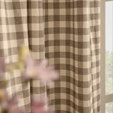 Harriet Gingham Cotton Pencil Pleat Curtains in buttermilk and chocolate brown check, shown pleated by a window with soft folds, styled with pink flowers in the foreground.