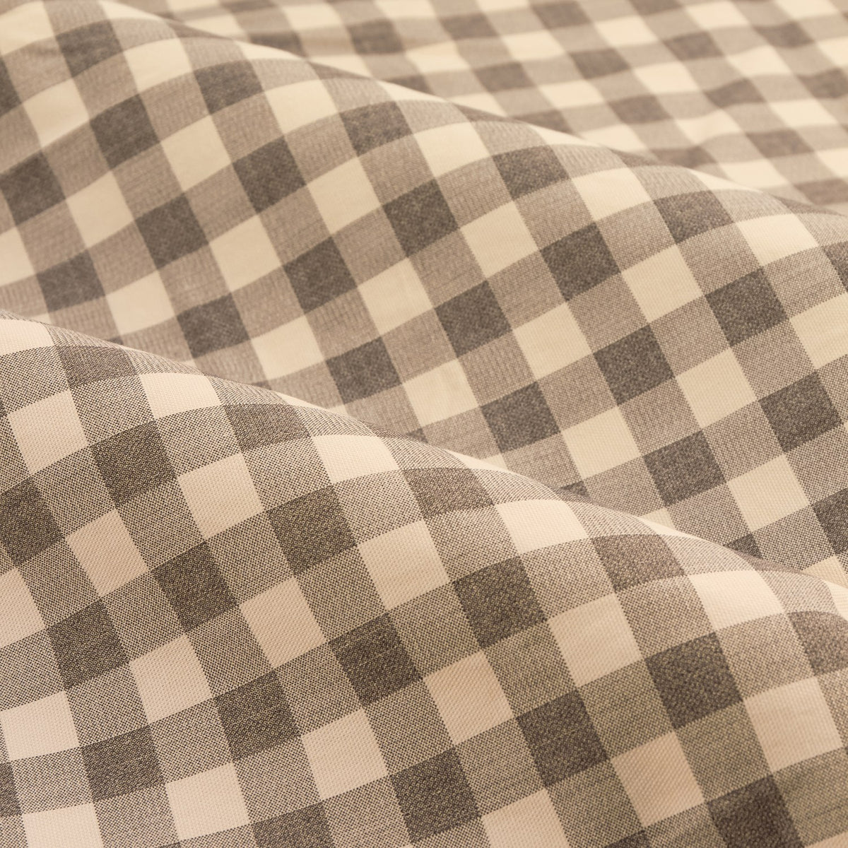 Close-up of Harriet Gingham cotton pencil pleat curtain fabric, showing a buttermilk and chocolate brown check pattern draped in soft folds.