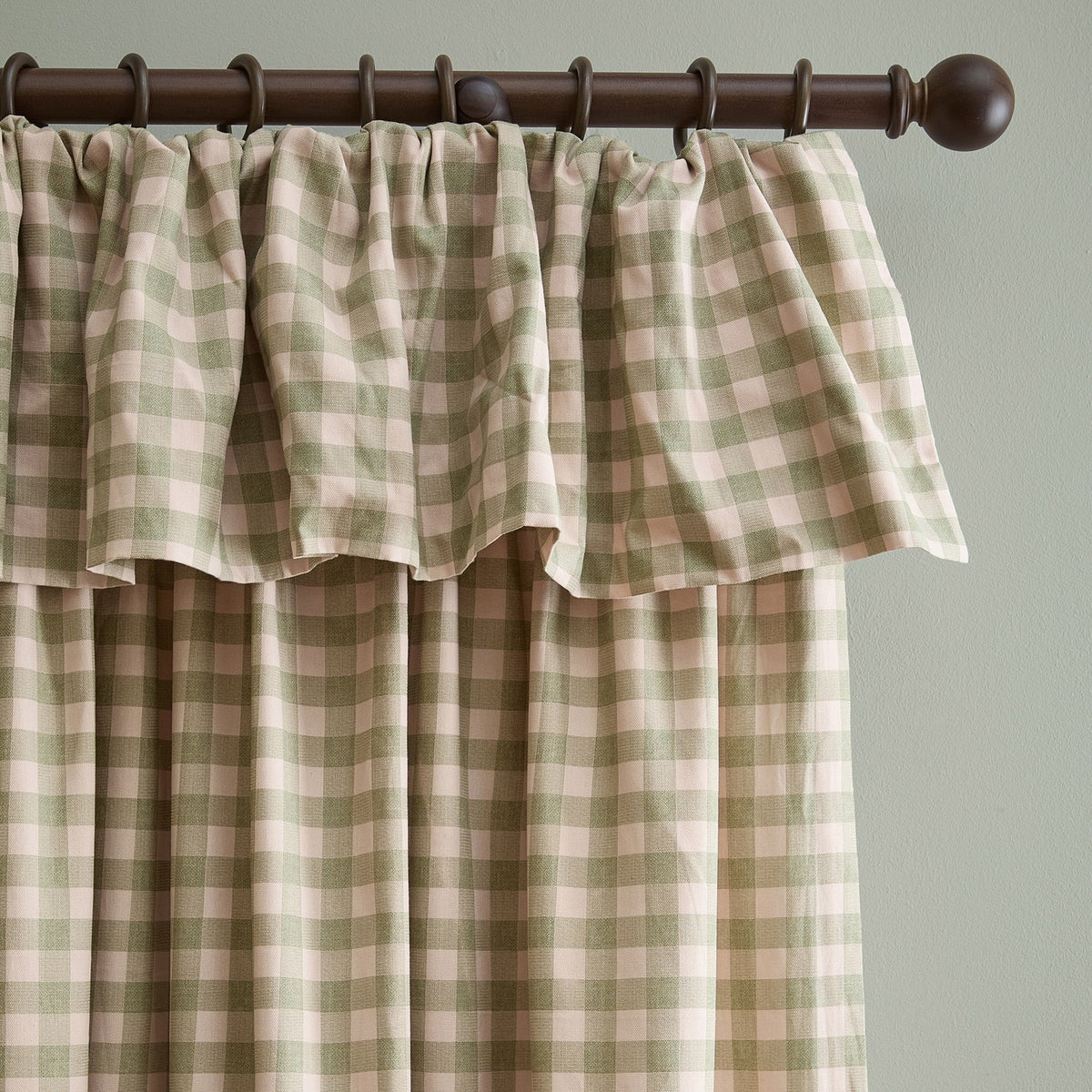 Harriet Gingham Cotton Pencil Pleat Curtains in pink and green check, showing a ruffled frill header on a dark wood curtain pole against a light wall.