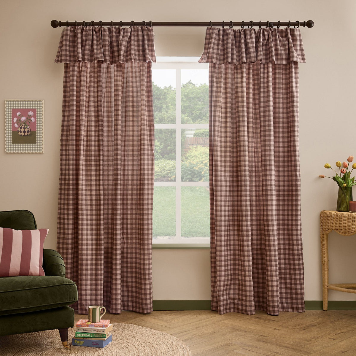 Harriet Gingham cotton pencil pleat curtains in Rose/Chocolate frame a window, showing the ruffled header and check pattern beside a green armchair and wicker table.