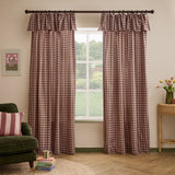 Harriet Gingham cotton pencil pleat curtains in Rose/Chocolate frame a window, showing the ruffled header and check pattern beside a green armchair and wicker table.