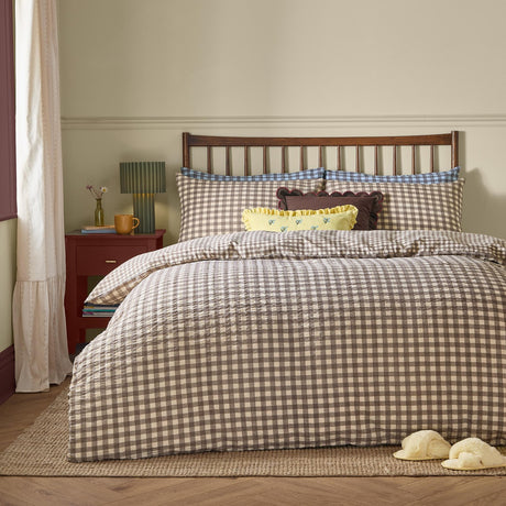 Harriet Gingham Check Duvet Cover Set in buttermilk and chocolate on a bed with striped pillowcases, a yellow ruffled cushion, and dark wooden headboard in a bedroom setting.