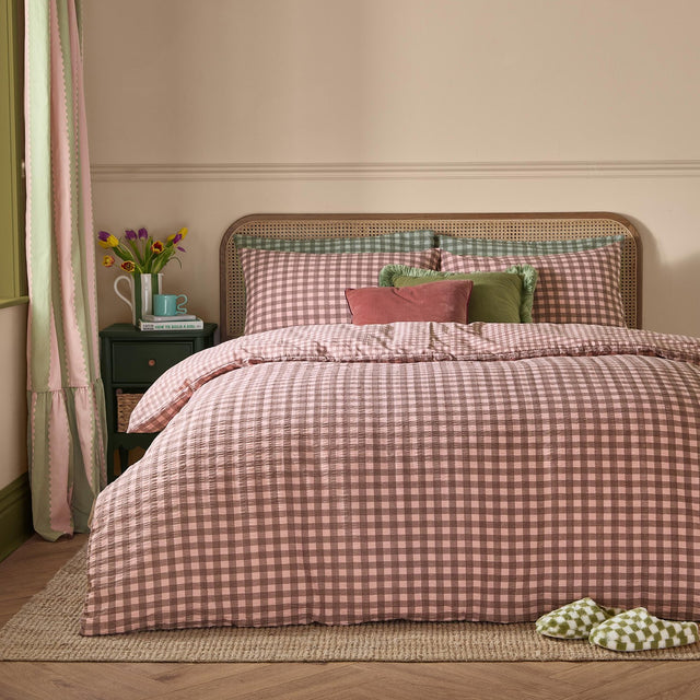 Harriet Gingham Cotton Check Duvet Cover Set in Rose/Chocolate, styled on a bed with matching pillowcases, velvet cushions, and a rattan headboard in a bedroom setting.