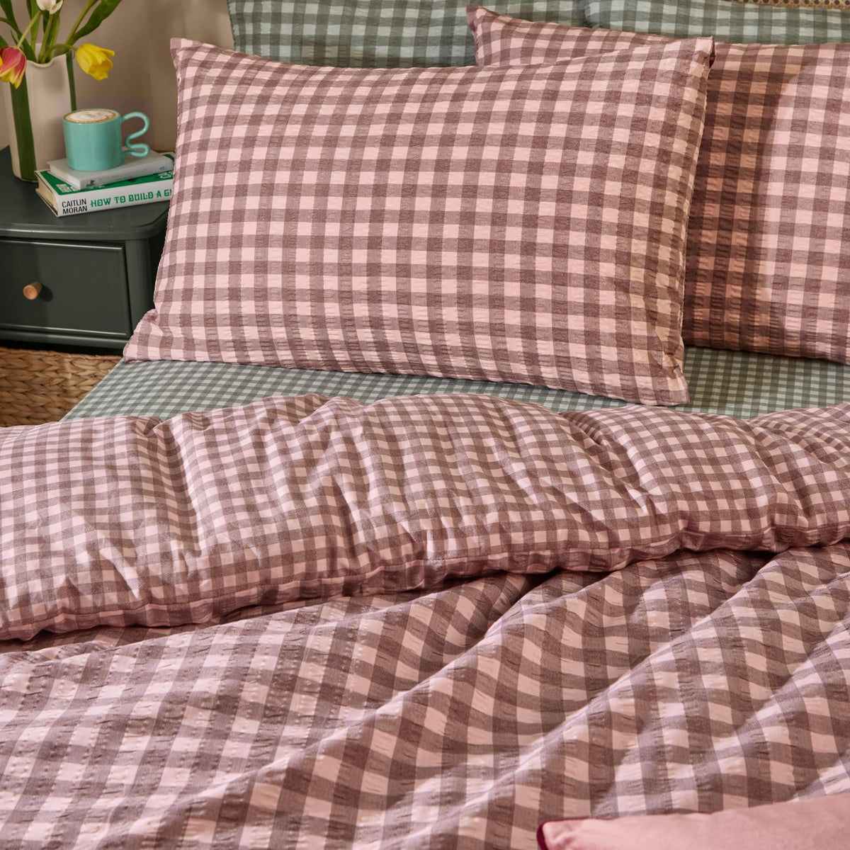 Harriet Gingham Cotton Check Duvet Cover Set in Rose/Chocolate, shown on a bed with matching pillowcases in a seersucker check, styled in a bedroom with a green nightstand and books.