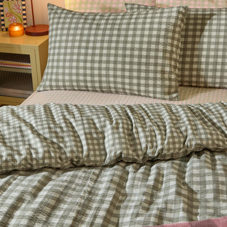 Harriet Gingham reversible cotton pillowcase pair in baygreen/mist, shown on bed pillows with a seersucker-textured check pattern in a bedroom setting alongside matching bedding.