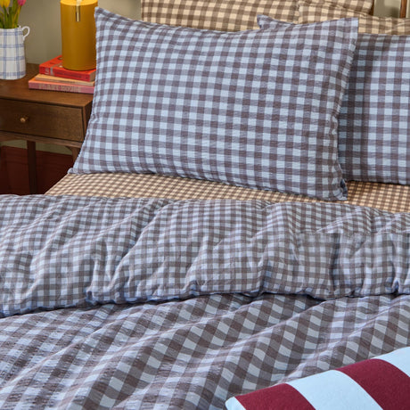 Harriet Gingham cotton pillowcase pair in blue/chocolate check, shown styled on a bed with matching duvet cover in a bedroom setting.